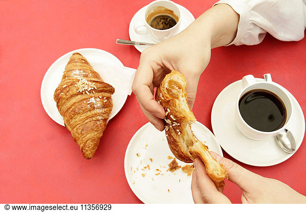 Close up of woman's hands breaking croissant at sidewalk cafe
