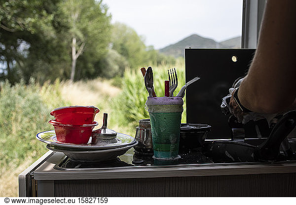 Close up of woman's hands washing dishes in motorhome.