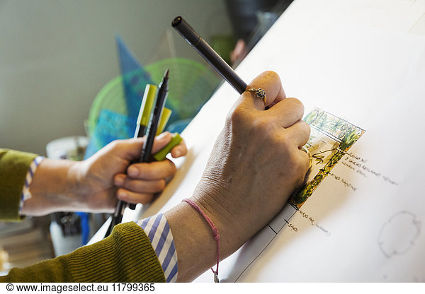 Close up of woman sitting at a drawing board  drawing with a fine liner pen  using a design template.