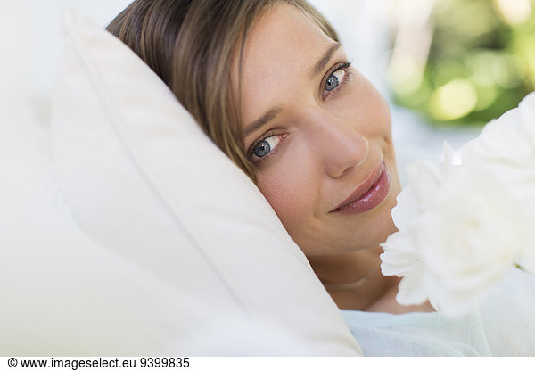 Close up of woman smelling flower on bed