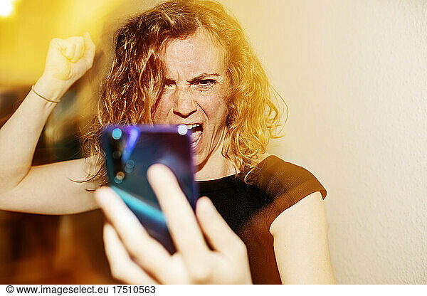 Close-up of woman talking aggressively on video call over smart phone at home