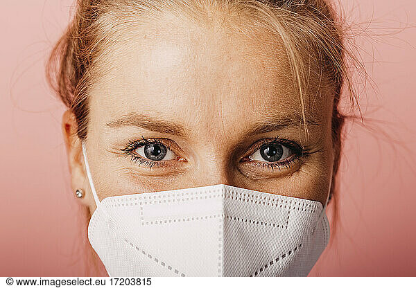 Close-up of woman wearing protective face mask against colored background