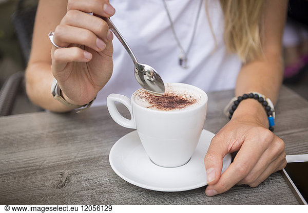 Close-up of woman with cappuccino in a street cafe