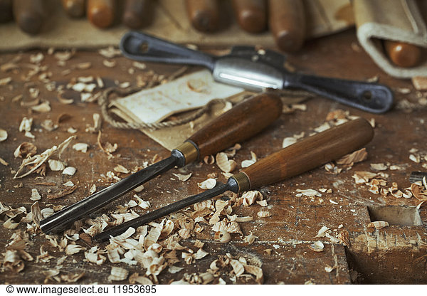 Close up of wood carving hand tools  chisels and wood shavings on a bench in a carver's workshop.
