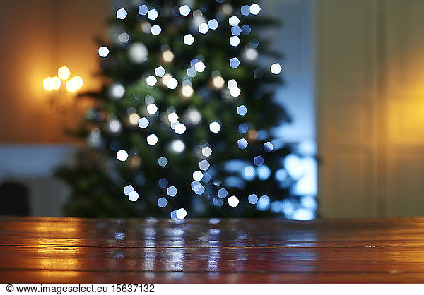 Close-up of wooden table with illuminated Christmas tree in background at home