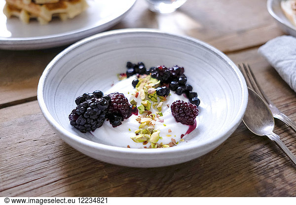 Close-up of yogurt with blackberries and pistachios in bowl at table