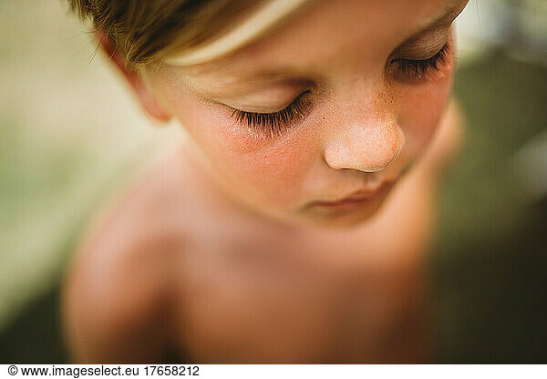 Close up of young boy's blonde eyelashes with eyes closed in summer