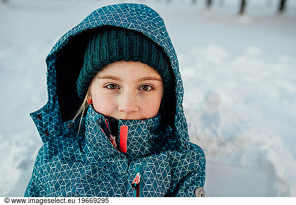 Close up of young girl with freckles looking directly at camera