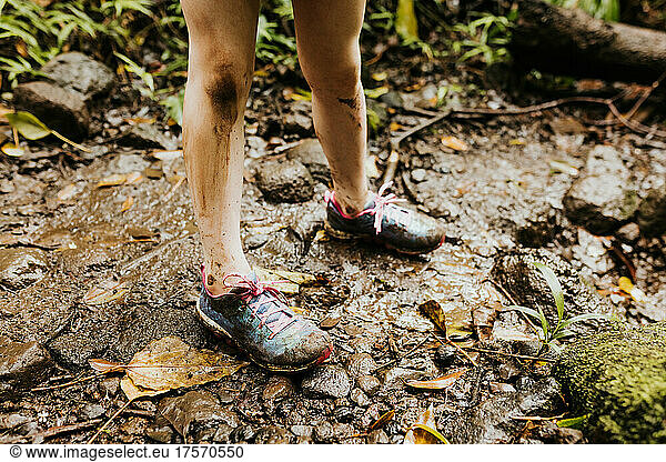 Close up of young girls muddy shoes and legs while hiking in Hawaii