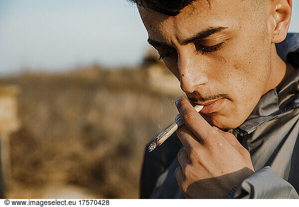 Close-up of young man smoking a marijuana joint outdoors