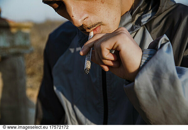 Close-up of young man smoking a marijuana joint outdoors