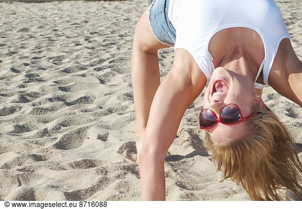 Close up of young woman bending over backwards on beach