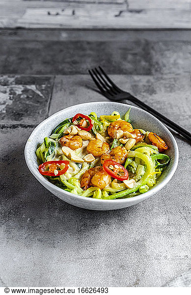 Close-up of zoodles with shrimps and chili in bowl served on table