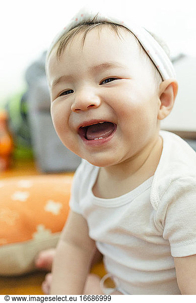 Close-up portrait of adorable Asian baby girl smiling at camera