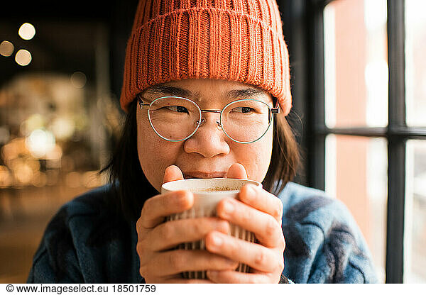 Close up portrait of Asian woman drinking coffee in a cafe