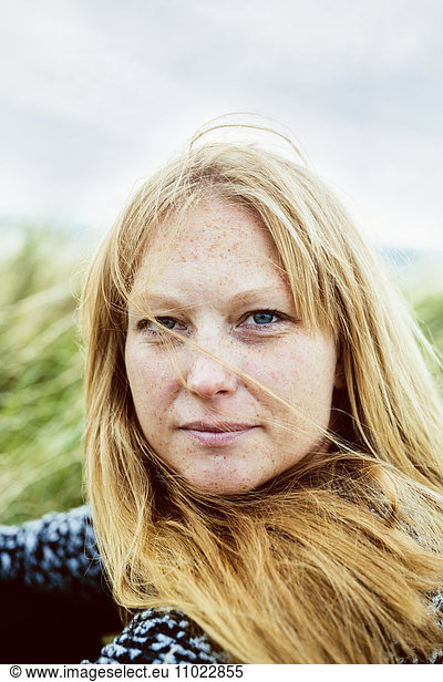Close-up portrait of blond woman sitting on field