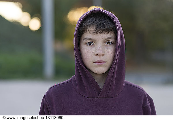 close-up portrait of boy in hooded shirt standing outdoors