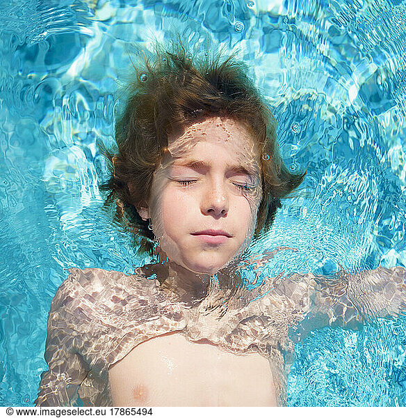 Close up portrait of boy in swimming pool with closed eyes