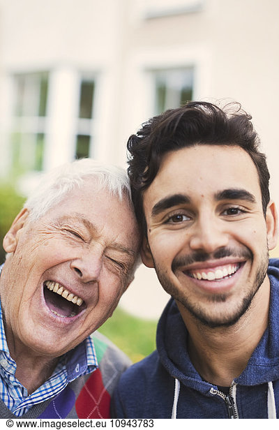 Close-up portrait of caretaker with happy senior man outside nursing home