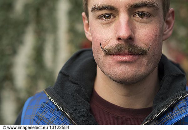Close-up portrait of confident man with mustache at backyard