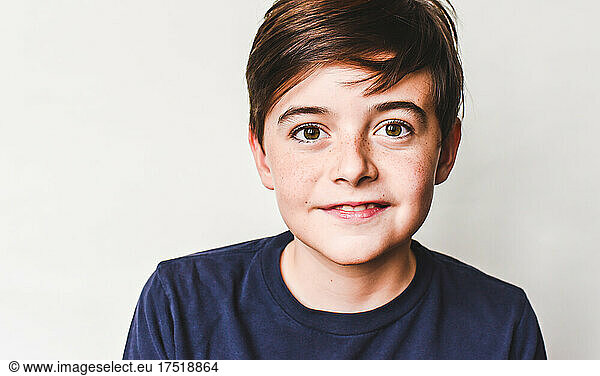 Close up portrait of cute young boy with brown hair and freckles.