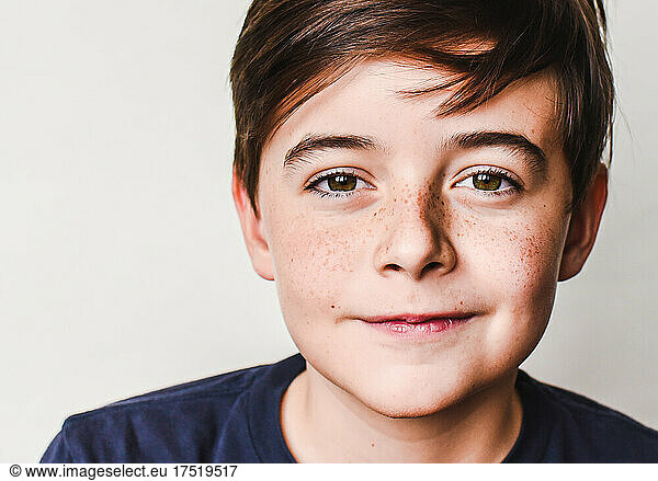 Close up portrait of cute young boy with brown hair and freckles.