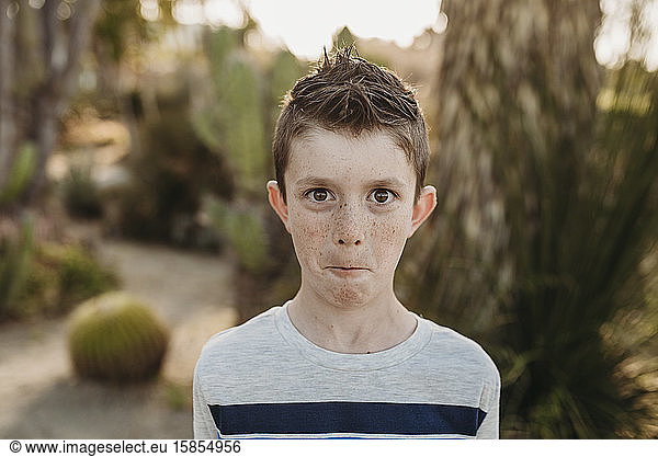 Close up portrait of cute young boy with freckles making funny face