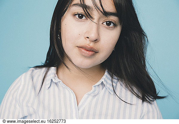 Close-up portrait of girl against blue background