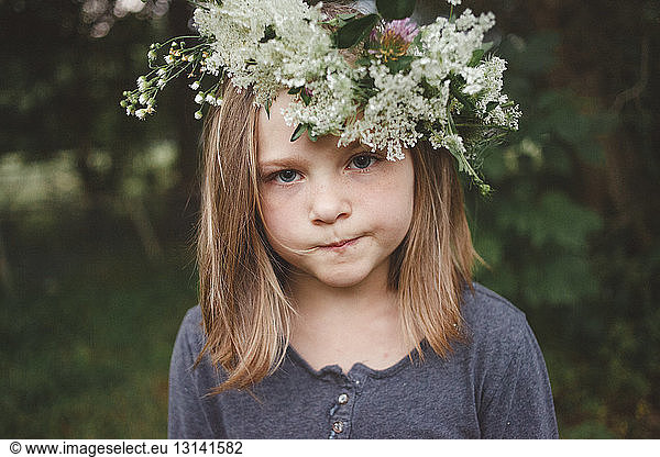 Close-up portrait of girl wearing flowers while standing at farm