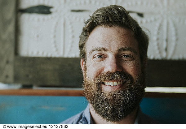 Close-up portrait of happy man with beard sitting at home