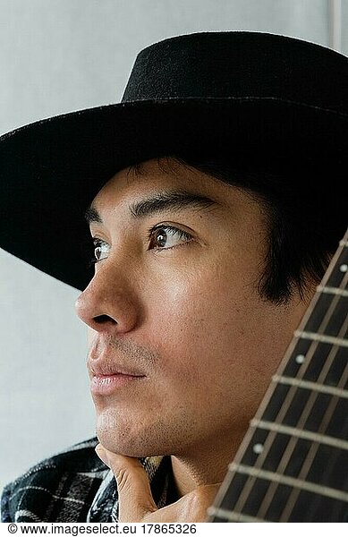 Close up portrait of latin man with the guitar looking away