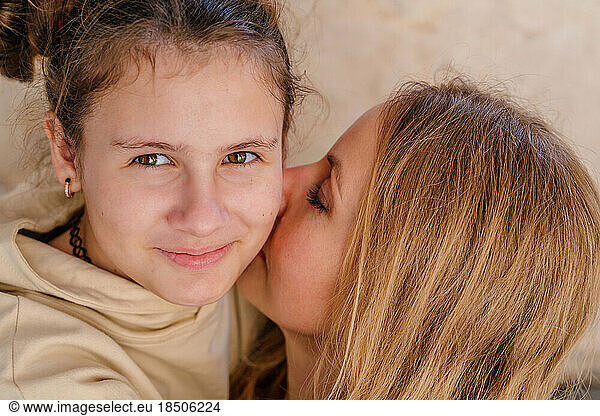 Close-up portrait of smiling mother and teenage daughter.