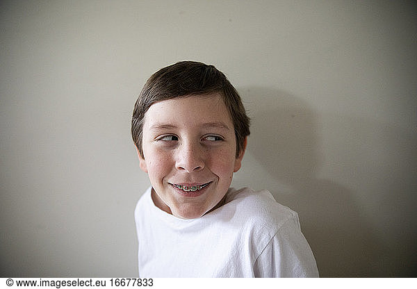 Close Up Portrait of Tween Boy With Braces Smiling Looking Off Camera