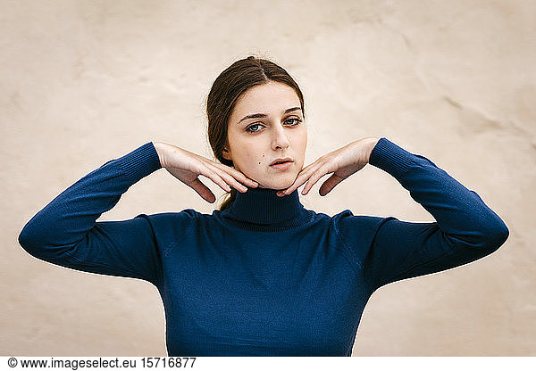 Close up portrait of woman with blue turtleneck pullover  hands on chin