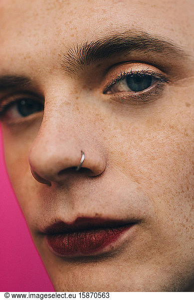 Close-up portrait of young man against pink background