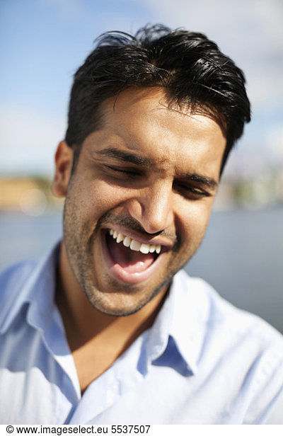 Close-up portrait of young man laughing outdoors