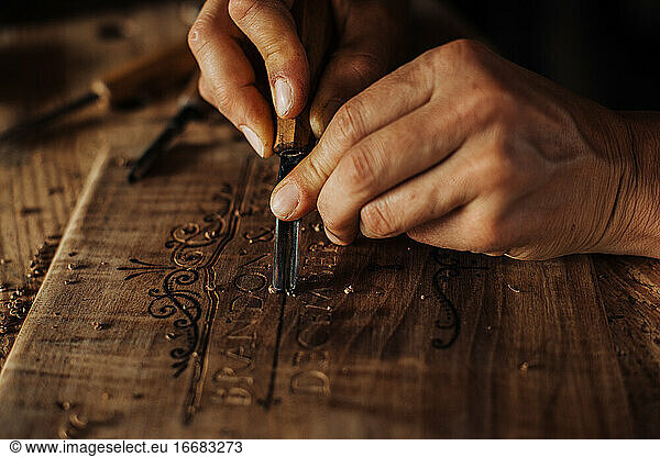 Close up process of decorative wood engraving using hand tools