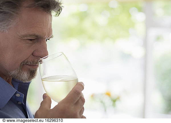 Close up senior man smelling and tasting white wine