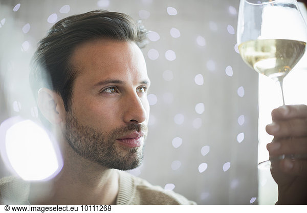 Close up serious man examining white wine