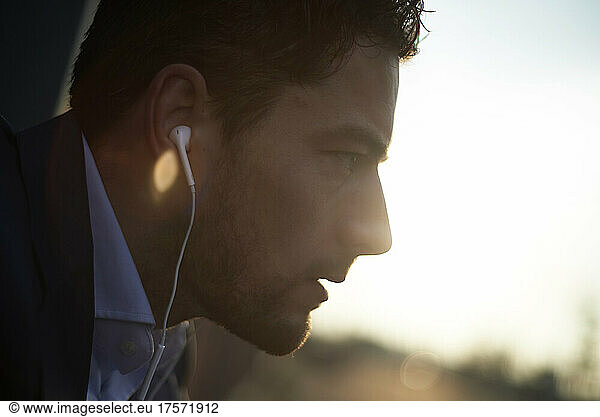 Close up side profile of a business man with earbuds in