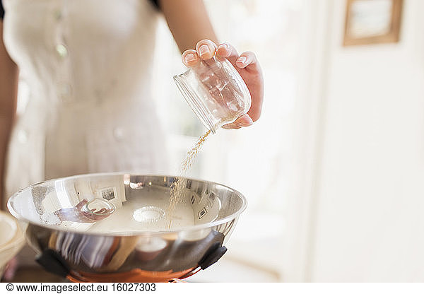 Close up teenage girl adding baking ingredient to bowl