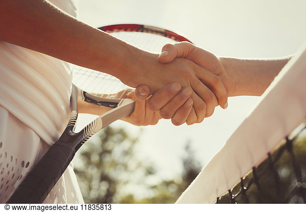 Close up tennis players handshaking in sportsmanship at net