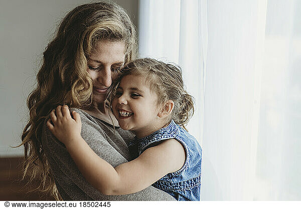 Close up view of mother and young daughter cuddling and laughing