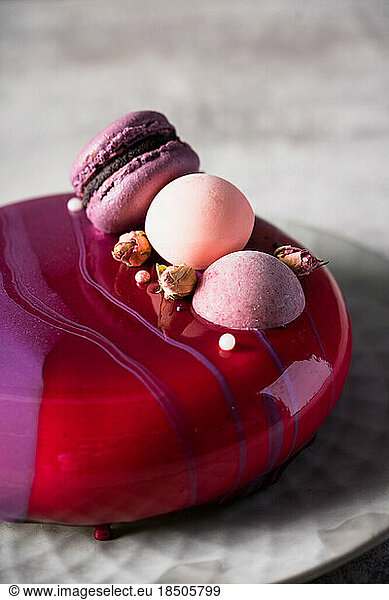Close up view on a pink purple cheese cake decorated by macaroons and