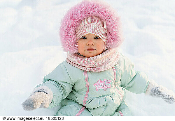 Close up winter portrait of a cute ruddy girl toddler in a snow