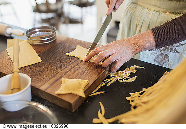 Close up woman cutting fresh homemade pasta