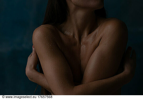Close up woman in water drops embracing herself by hands