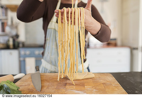 Close up woman making fresh homemade pasta in kitchen