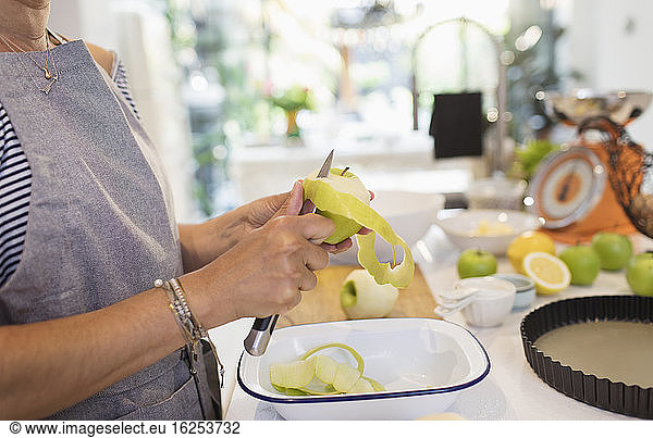 Close up woman slicing green apples for pie in kitchen
