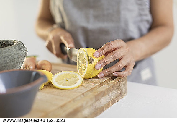 Close up woman slicing lemon on cutting board